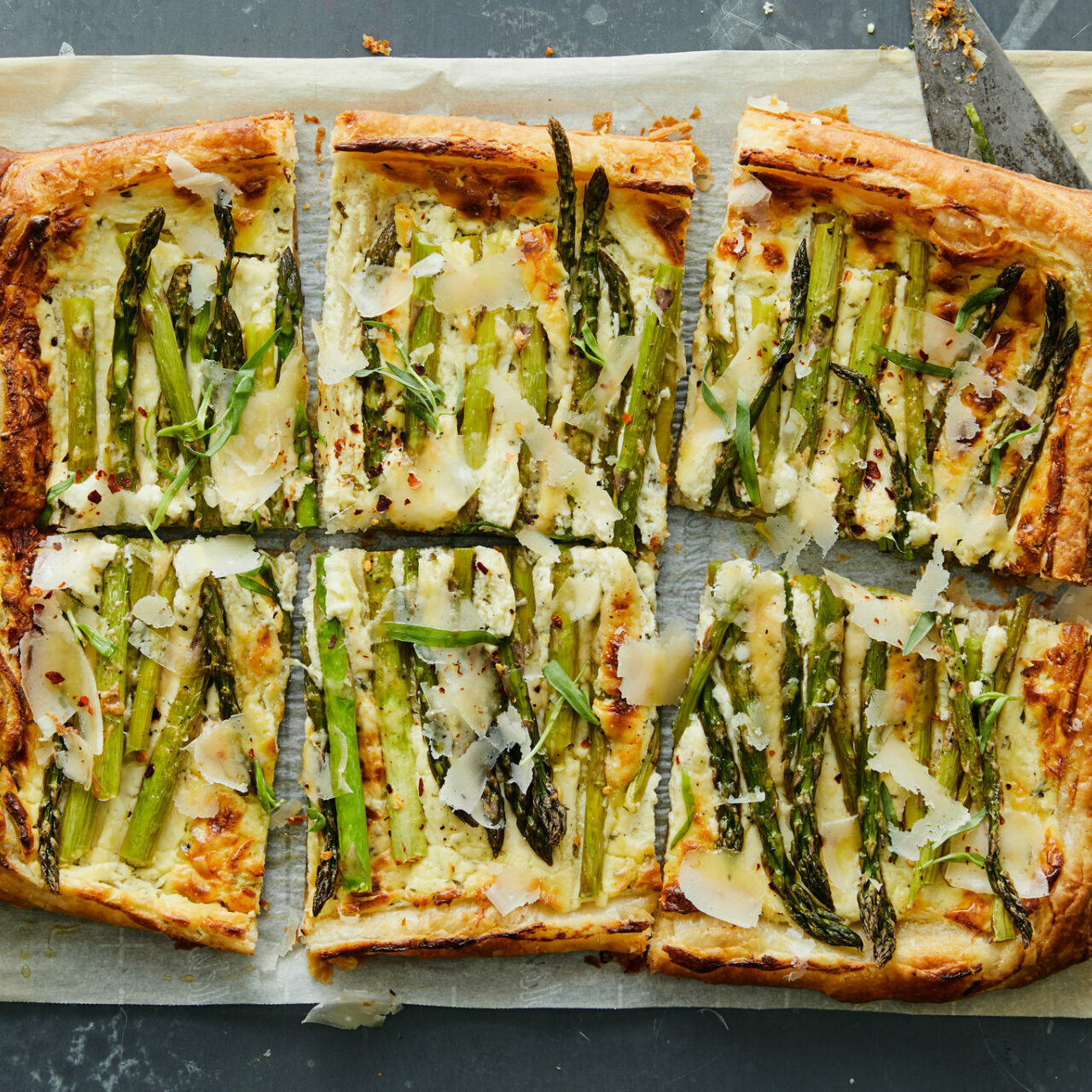 Tarte aux asperges, chèvre et parmesan coupé sur du papier allant au four