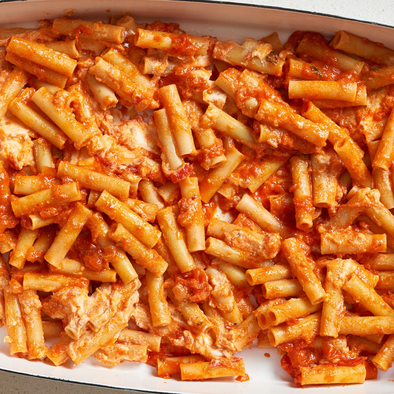 pâtes ziti avec de la sauce tomate, de la viande et du fromage dans un plat blanc allant au four