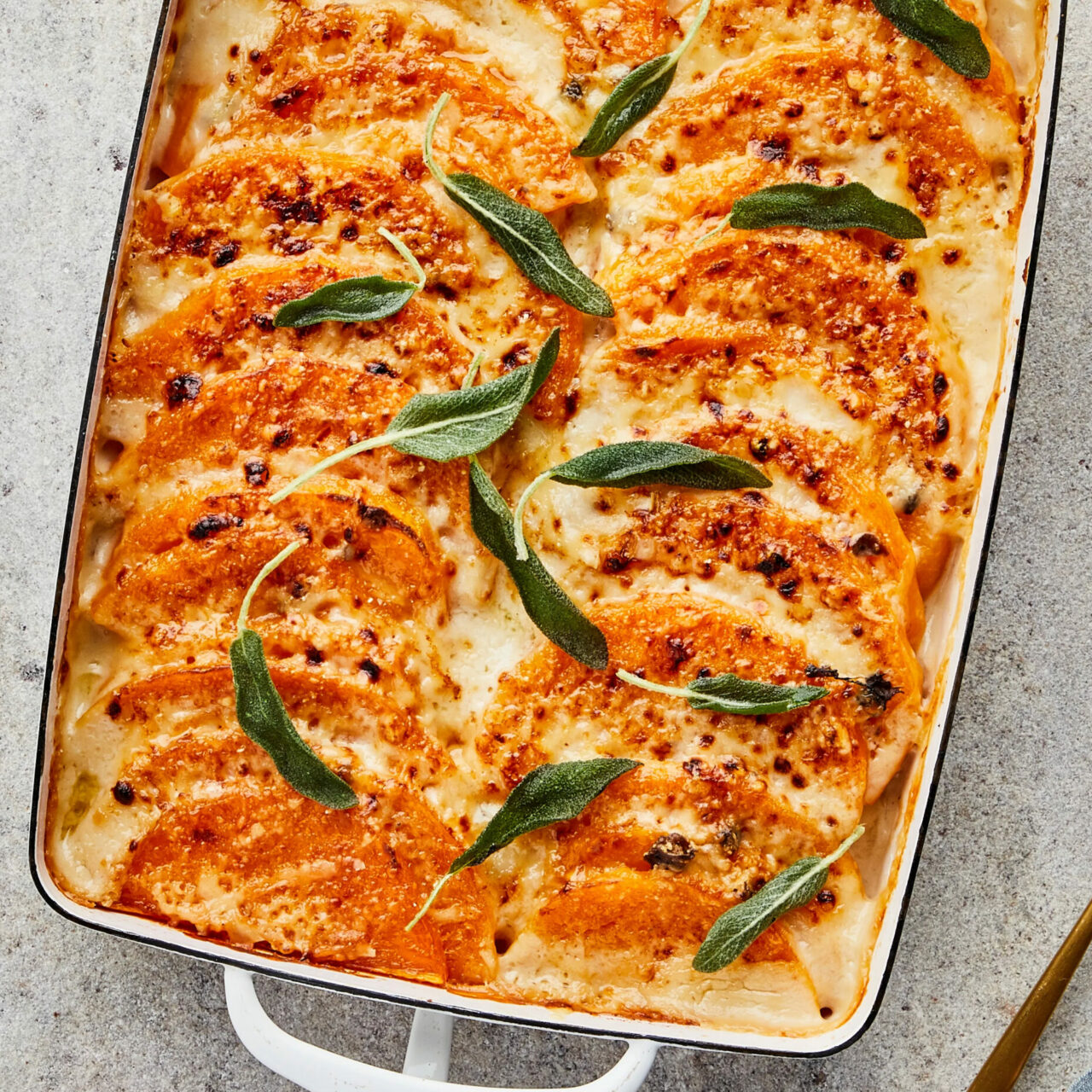 Gratin de potimarron au fromage avec des feuilles de romarin dans un plat allant au four