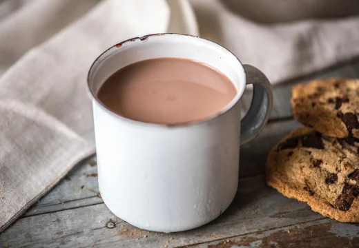 Chocolat chaud dans une tasse blanche sur une table avec des cookies à côté