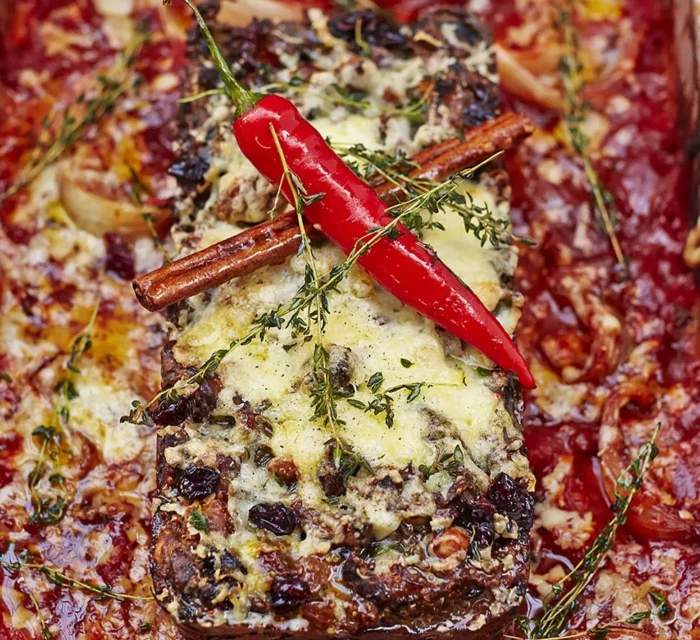 roti de noix dans une sauce rouge avec un piment rouge, de la cannelle et du fromage fondu