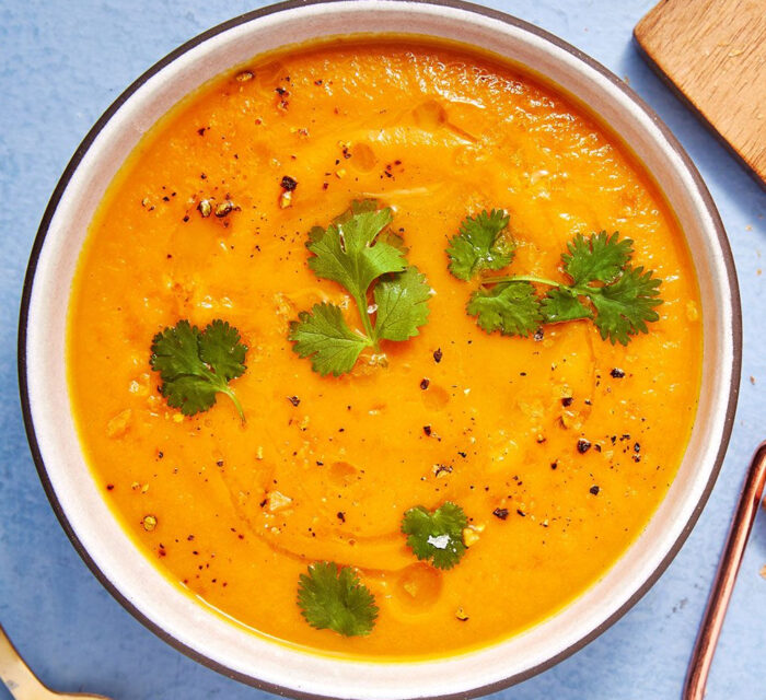 soupe à la carotte et à l'orange avec des morceaux de coriandre par dessus