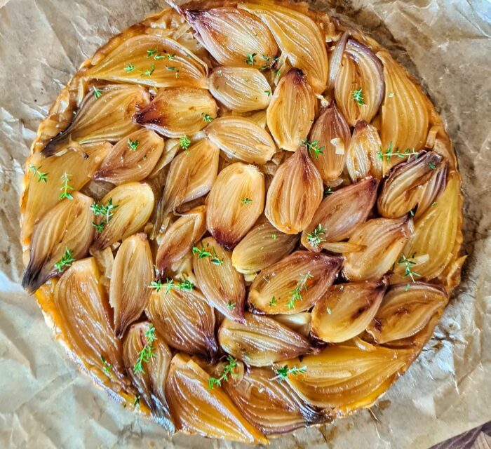 Tarte tatin d'échalotes avec un thym sur du papier cuisson