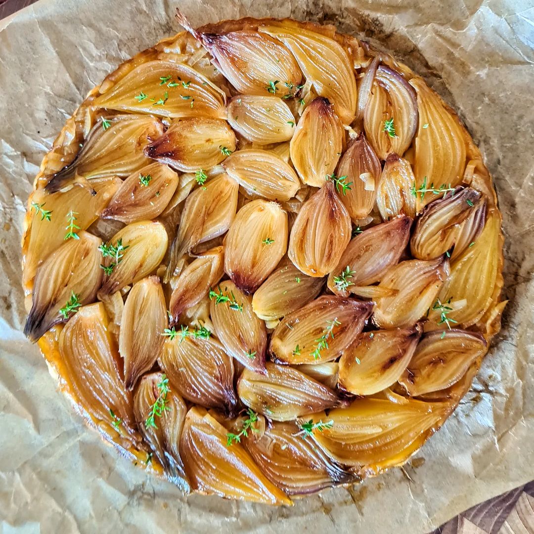 Tarte tatin d'échalotes avec un thym sur du papier cuisson