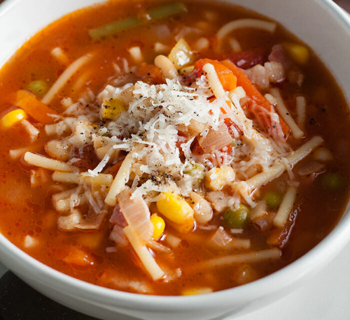 soupe de légumes avec un bouillon et des pâtes dans un bol blanc