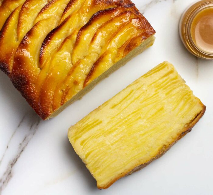 gâteau invisible aux pommes coupé en tranches avec un pot de sauce sur le côté