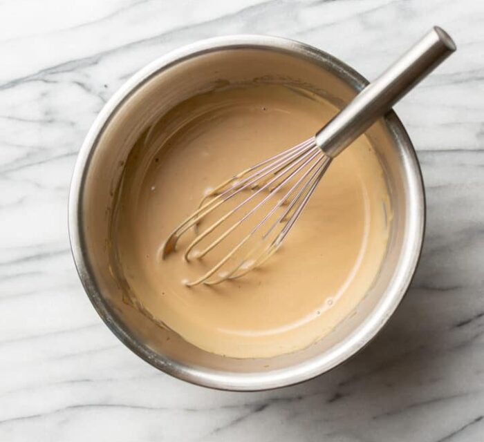 vinaigrette crémeuse avec un fouet dans un bol sur du marbre