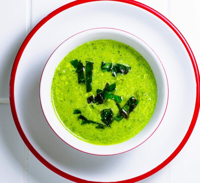 Soupe froide à la courgette avec du basilic, dans un bol blanc et assiette blanche