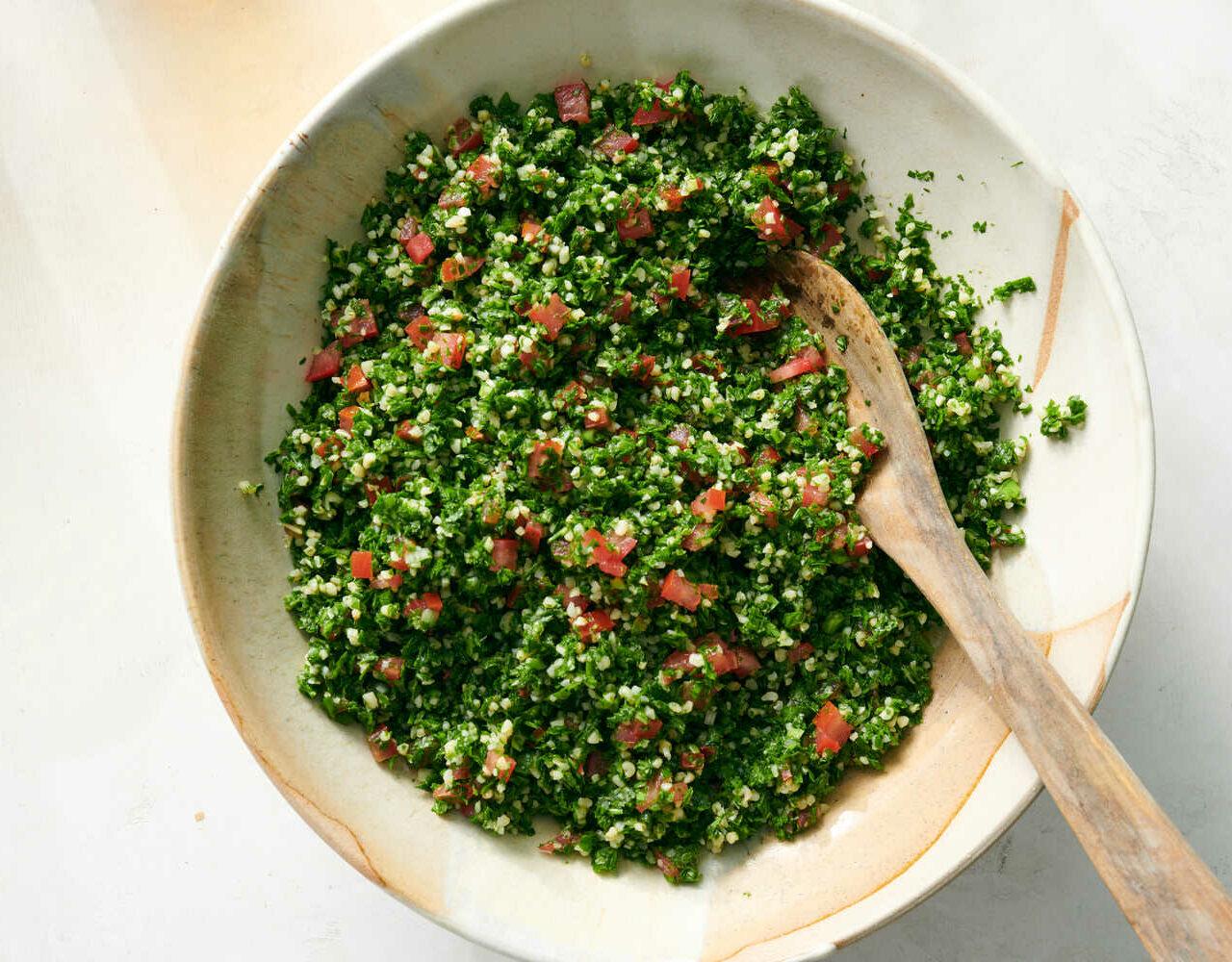 salade de taboulé servi dans un bol blanc et une cuillère en bois pour servir