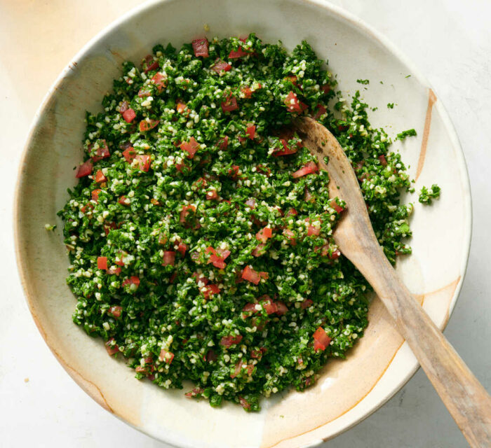 salade de taboulé servi dans un bol blanc et une cuillère en bois pour servir