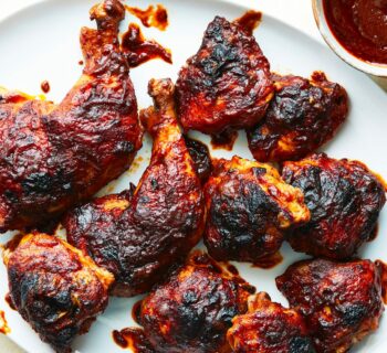 Poulet Barbecue servi dans un plat blanc avec la sauce barbecue sur le côté