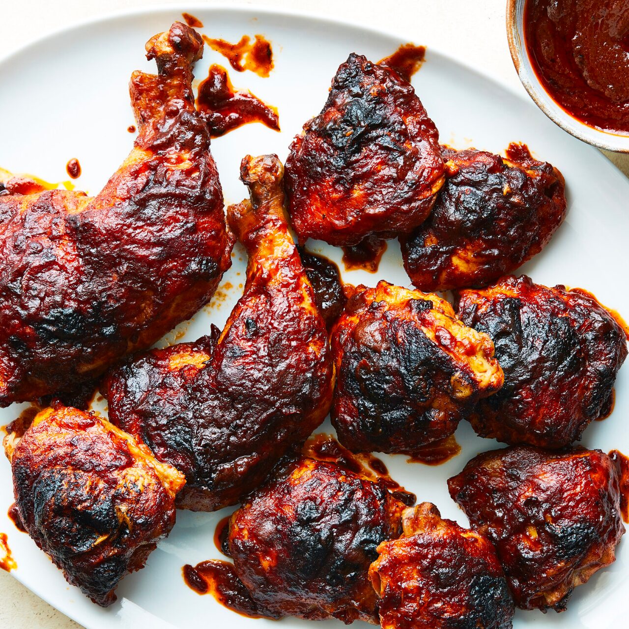 Poulet Barbecue servi dans un plat blanc avec la sauce barbecue sur le côté