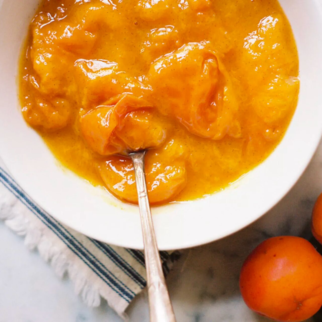 Compote d'abricot servie dans un bol blanc avec une cuillère
