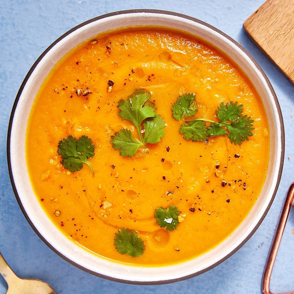soupe à la carotte et à l'orange avec des morceaux de coriandre par dessus