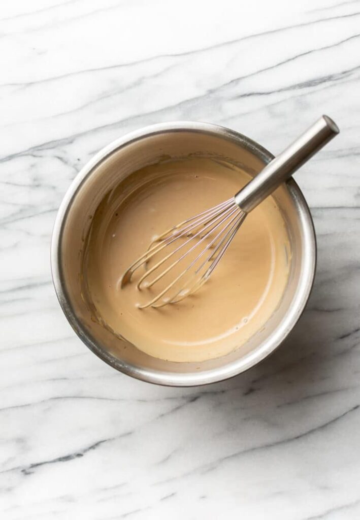 vinaigrette crémeuse avec un fouet dans un bol sur du marbre