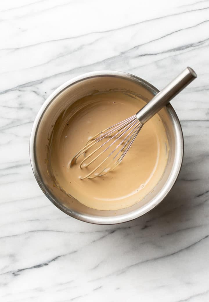 vinaigrette crémeuse avec un fouet dans un bol sur du marbre