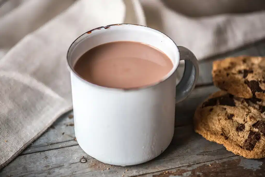 Chocolat chaud dans une tasse blanche sur une table avec des cookies à côté