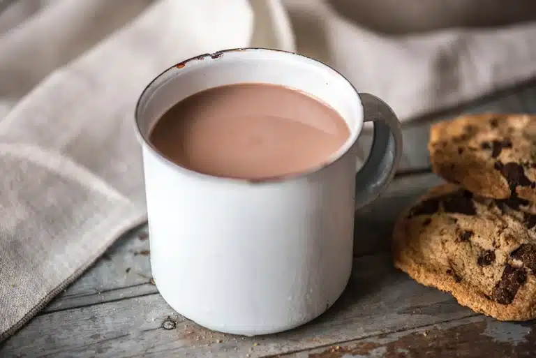 Chocolat chaud dans une tasse blanche sur une table avec des cookies à côté