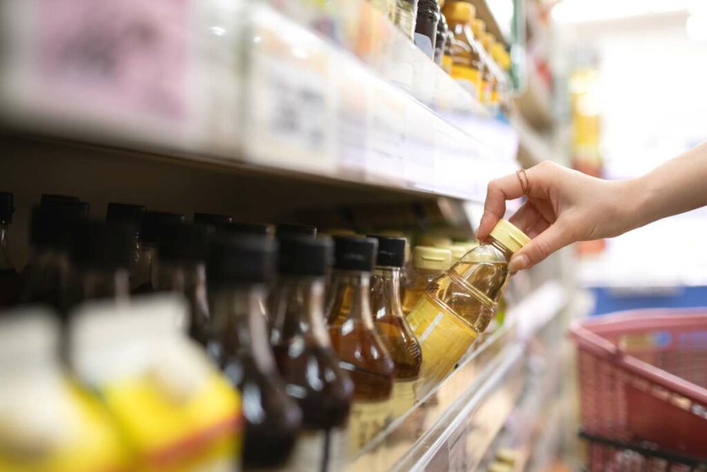 Main qui prend une bouteille de condiment dans un rayon de supermarché