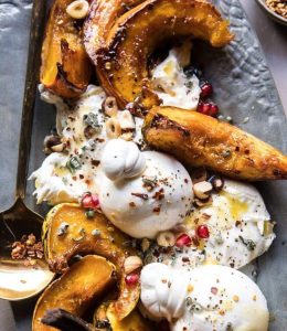 Courges et burrata cuits au four avec du buerre et du miel, servi dans un plat gris avec de la grenade