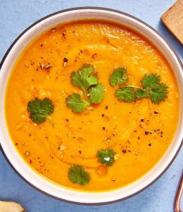 soupe à la carotte et à l'orange avec des morceaux de coriandre par dessus