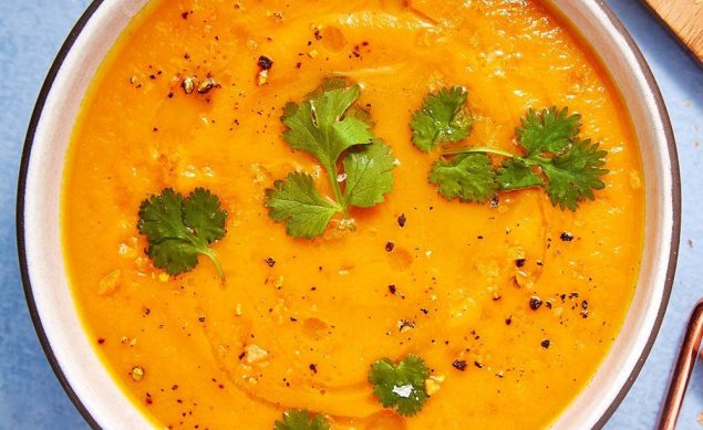 soupe à la carotte et à l'orange avec des morceaux de coriandre par dessus