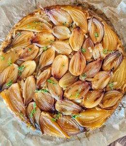 Tarte tatin d'échalotes avec un thym sur du papier cuisson