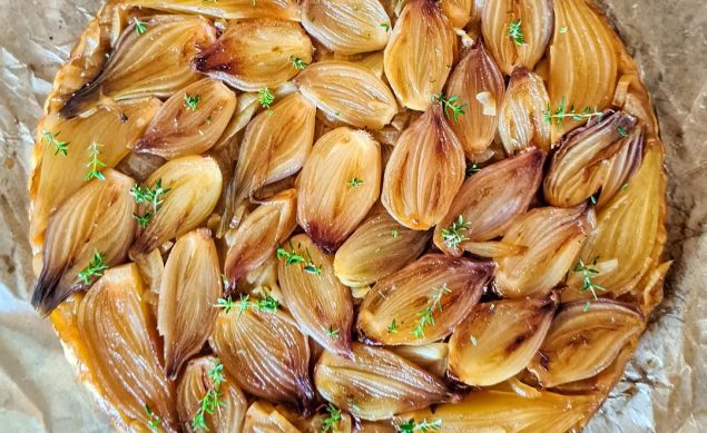 Tarte tatin d'échalotes avec un thym sur du papier cuisson