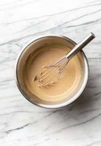 vinaigrette crémeuse avec un fouet dans un bol sur du marbre