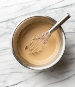 vinaigrette crémeuse avec un fouet dans un bol sur du marbre