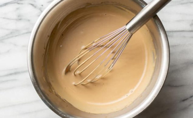 vinaigrette crémeuse avec un fouet dans un bol sur du marbre