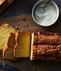 cake découpé sur une planche en bois avec un pot de yaourt à côté