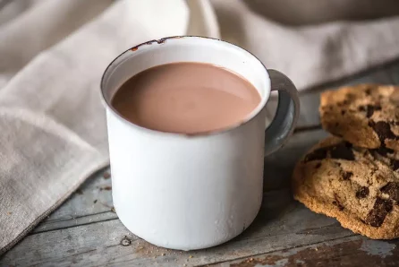 Chocolat chaud dans une tasse blanche sur une table avec des cookies à côté