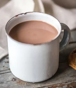 Chocolat chaud dans une tasse blanche sur une table avec des cookies à côté