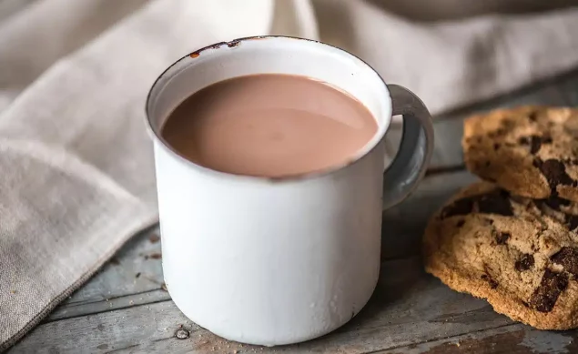 Chocolat chaud dans une tasse blanche sur une table avec des cookies à côté