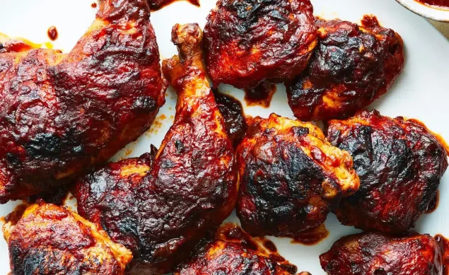 Poulet Barbecue servi dans un plat blanc avec la sauce barbecue sur le côté