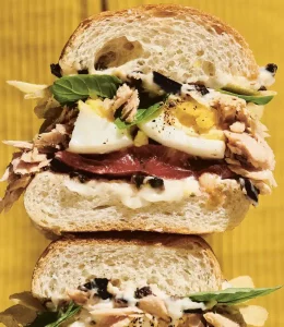 Sandwich au thon, aux œufs, salade, tomate, olives noires coupé en 2